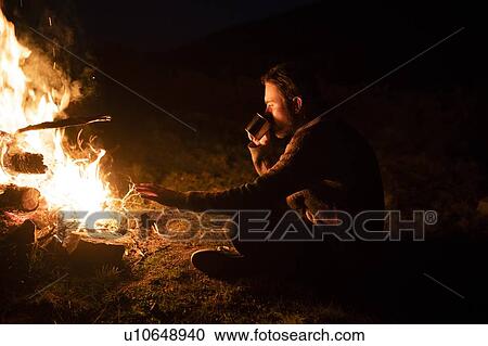 Man drinking by campfire View Large Photo Image Stock Image - Man drinking by campfire. Fotosearch