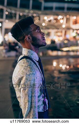 Stock Image - Man enjoying city view at night. Fotosearch