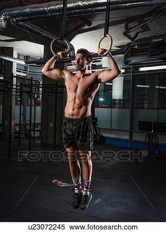 Man exercising with gymnastic rings in gym View Large Photo Image Stock Photography - Man exercising with gymnastic rings in gym. Fotosearch