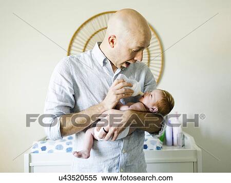 Stock Photography - Man feeding his baby son. Fotosearch