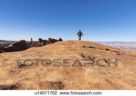 Stock Image - Man hiking on rock in Arches National Park, Utah, USA. Fotosearch