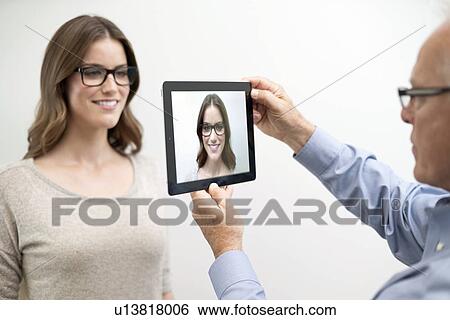 Man holding digital tablet in front of woman's face. View Large Photo Image Stock Photograph - Man holding digital tablet in front of woman's face.. Fotosearch