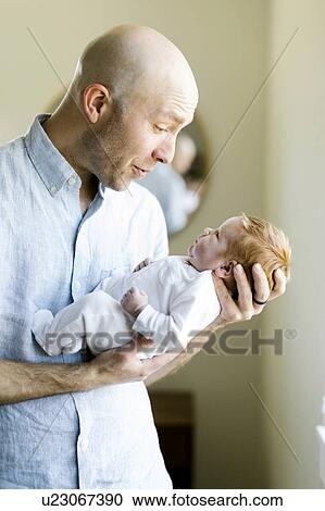 Stock Image - Man holding his baby son. Fotosearch
