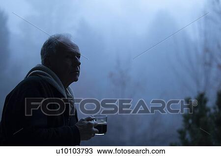 Stock Image - Man in shadow holding coffee cup by fog. Fotosearch