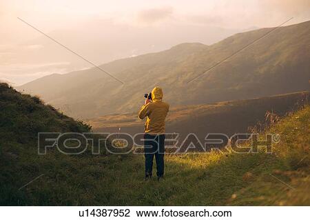 Man in yellow jacket taking photographs in the Carpathian Mountain Range View Large Photo Image Stock Image - Man in yellow jacket taking photographs in the Carpathian Mountain Range. Fotosearch