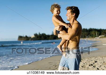 Stock Photo - Man playing with his son on beach. Fotosearch