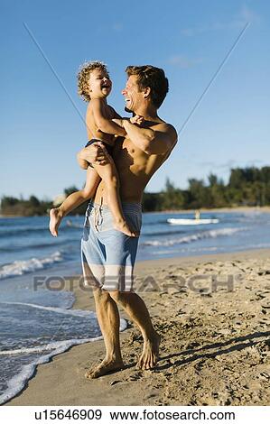 Stock Photo - Man playing with his son on beach. Fotosearch