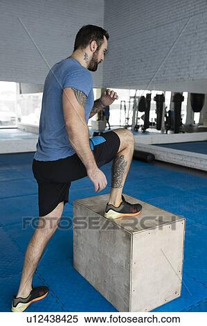 Stock Photography - Man stepping onto box in gym. Fotosearch