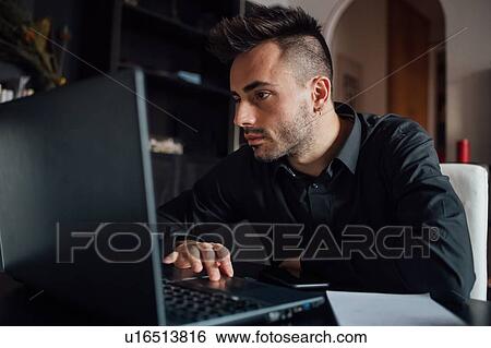 Stock Photograph - Man using laptop in home office. Fotosearch
