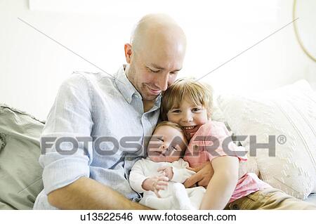 Stock Photograph - Man with his sons on sofa. Fotosearch