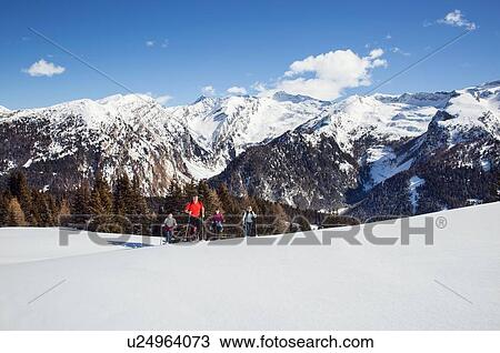 Stock Image - Mature couple and daughters snowshoeing in snow covered mountain landscape, Styria, Tyrol, Austria. Fotosearch