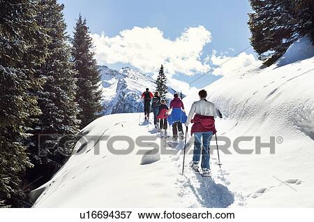 Stock Photo - Mature couple and daughters snowshoeing in snow covered mountain landscape, rear view, Styria, Tyrol, Austria. Fotosearch