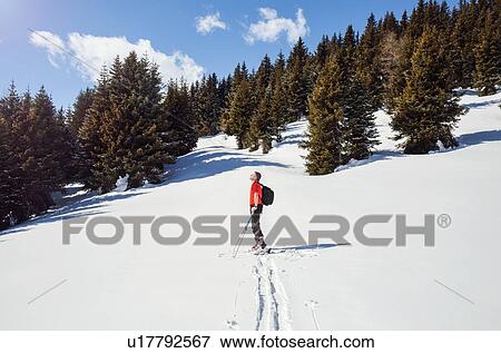 Stock Photo - Mature male snowshoer looking up from snow covered mountain landscape, Styria, Tyrol, Austria. Fotosearch