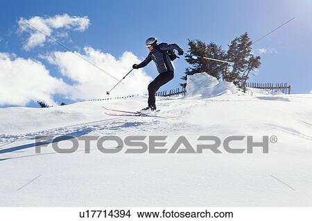 Picture - Mature man skiing down snow covered mountain, Styria, Tyrol, Austria. Fotosearch