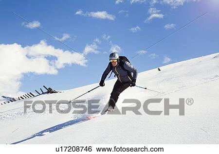 Stock Photograph - Mature man skiing down snow covered mountain, Styria, Tyrol, Austria. Fotosearch
