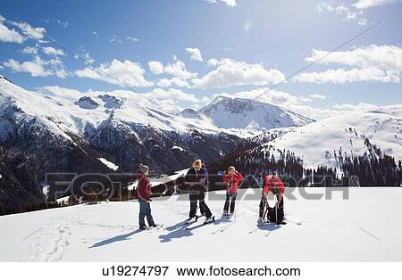 Stock Photo - Mature woman and daughters taking a break while snowshoeing on snow covered mountainside, Styria, Tyrol, Austria. Fotosearch