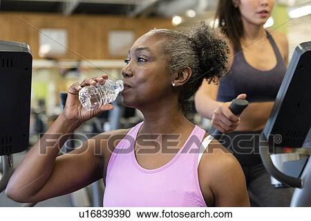 Mature woman drinking water on break in gym View Large Photo Image Stock Image - Mature woman drinking water on break in gym. Fotosearch