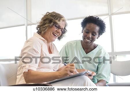Mature woman filling out form with nurse, smiling. View Large Photo Image Stock Photograph - Mature woman filling out form with nurse, smiling.. Fotosearch