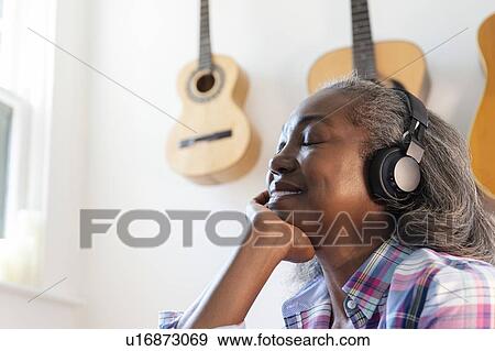Stock Photo - Mature woman listening to music on headphones. Fotosearch