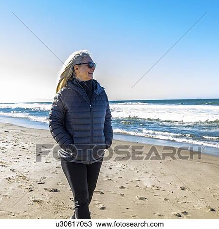 Mature woman walking on beach View Large Photo Image Stock Image - Mature woman walking on beach. Fotosearch
