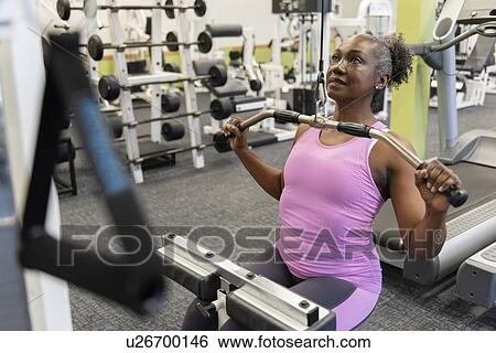 Stock Photograph - Mature woman weight training in gym. Fotosearch