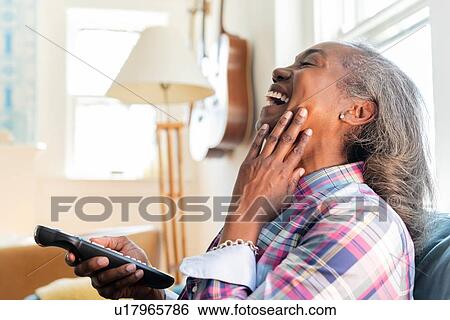 Mature woman with remote control watching television View Large Photo Image Stock Photograph - Mature woman with remote control watching television. Fotosearch