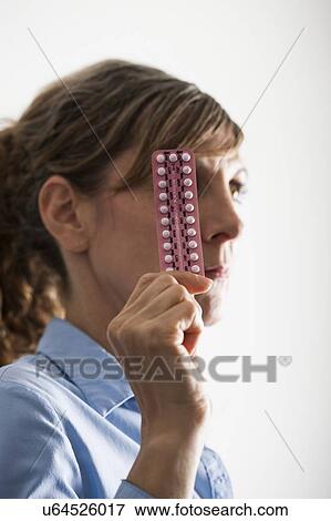Stock Photo - Menopausal woman with hormone replacement therapy (HRT) pills. HRT pills are synthetic hormones used to treat menopausal women. They counteract the hormone deficiency that occurs at menopause.. Fotosearch