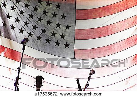Stock Image - Microphones and guitar by American Flag. Fotosearch