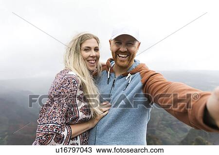 Stock Image - Mid adult couple taking selfie. Fotosearch
