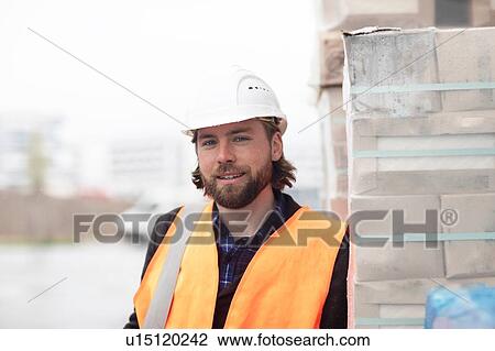 Mid adult male civil engineer leaning against stacked building material on construction site, portrait View Large Photo Image Stock Image - Mid adult male civil engineer leaning against stacked building material on construction site, portrait. Fotosearch