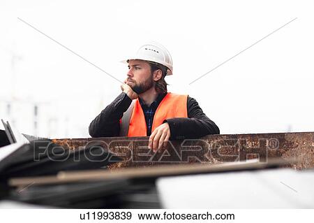 Mid adult male construction worker leaning against waste skip contemplating View Large Photo Image Stock Photo - Mid adult male construction worker leaning against waste skip contemplating. Fotosearch