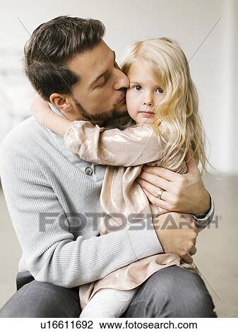 Mid adult man kissing his daughter on the cheek View Large Photo Image Stock Image - Mid adult man kissing his daughter on the cheek. Fotosearch