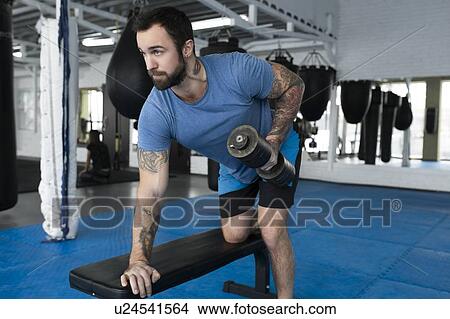 Picture - Mid adult man lifting dumbbell in gym. Fotosearch