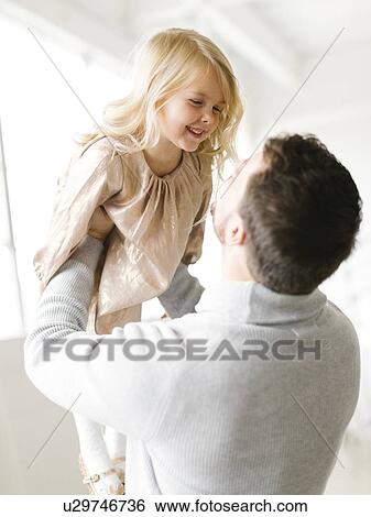 Mid adult man lifting his daughter View Large Photo Image Stock Photograph - Mid adult man lifting his daughter. Fotosearch