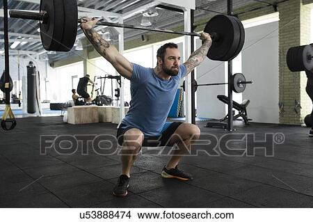 Picture - Mid adult man weight lifting in gym. Fotosearch