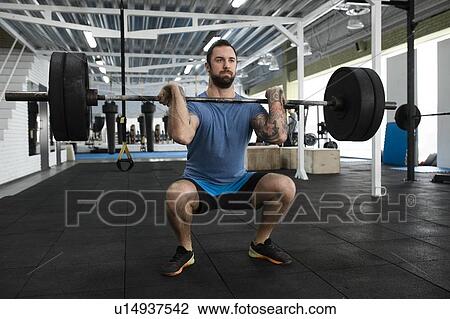 Stock Image - Mid adult man weight lifting in gym. Fotosearch