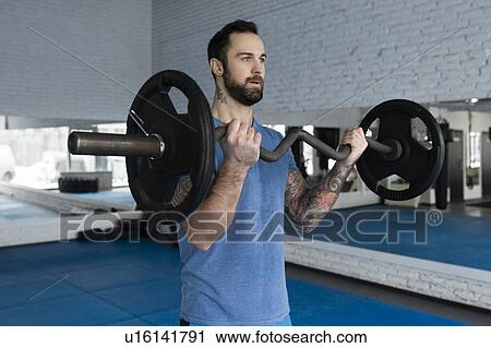 Stock Image - Mid adult man weight lifting in gym. Fotosearch