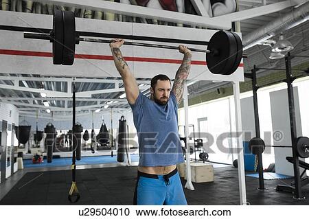 Mid adult man weight lifting in gym View Large Photo Image Stock Image - Mid adult man weight lifting in gym. Fotosearch