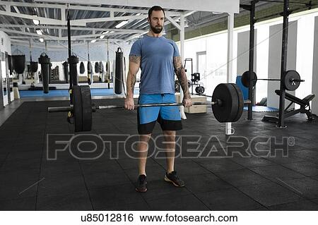 Stock Photograph - Mid adult man weight lifting in gym. Fotosearch