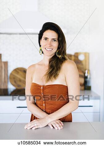 Mid adult woman smiling in kitchen View Large Photo Image Picture - Mid adult woman smiling in kitchen. Fotosearch