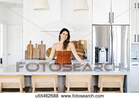 Stock Photo - Mid adult woman smiling in kitchen. Fotosearch