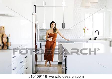 Mid adult woman smiling in kitchen View Large Photo Image Stock Photograph - Mid adult woman smiling in kitchen. Fotosearch