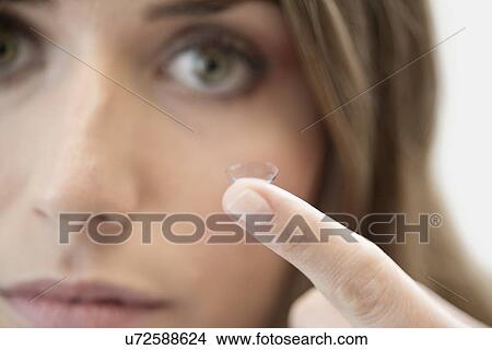 Picture - Mid adult woman with contact lens on finger.. Fotosearch