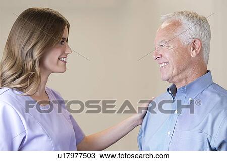 Stock Image - Mid adult woman with hand on senior man's shoulder.. Fotosearch
