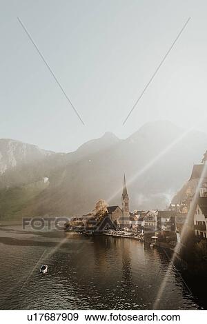 Stock Photo - Mist and sun rays over lakeside village, elevated view, Hallstatt, Upper Austria. Fotosearch
