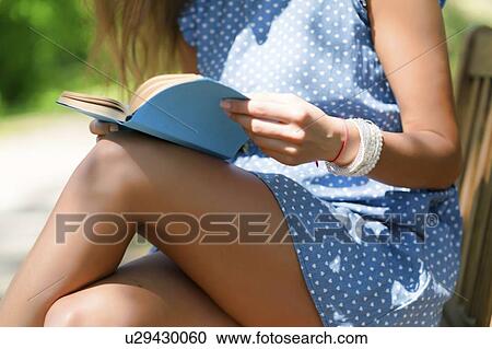 Stock Image - MODEL RELEASED. Close-up of a woman reading in a park.. Fotosearch