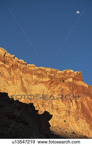 Stock Photo - Moon over cliff in shadow in Capitol Reef National Park, USA. Fotosearch