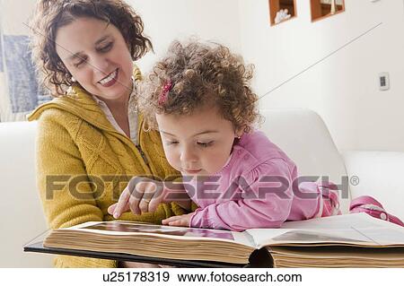 Stock Photo - Mother and daughter reading picture book. Fotosearch
