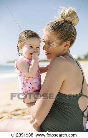 Stock Photo - Mother carrying her baby girl on beach. Fotosearch