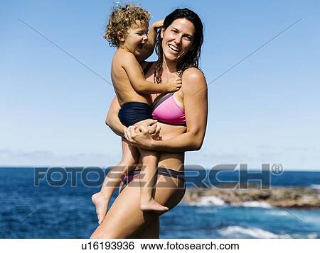Stock Photograph - Mother carrying her son by sea. Fotosearch